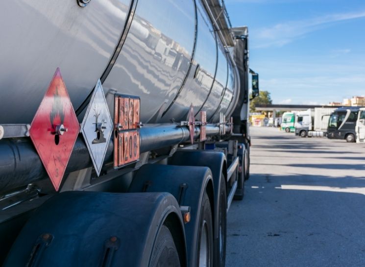 Detalhe lateral de caminhão-tanque com rótulos de risco e painéis de segurança aplicados conforme a NBR 7500 e legislações para caminhão-tanque.