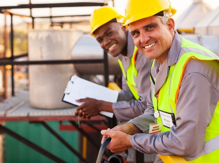 técnicos sorrindo em uma área industrial - teste de mangueiras industriais
