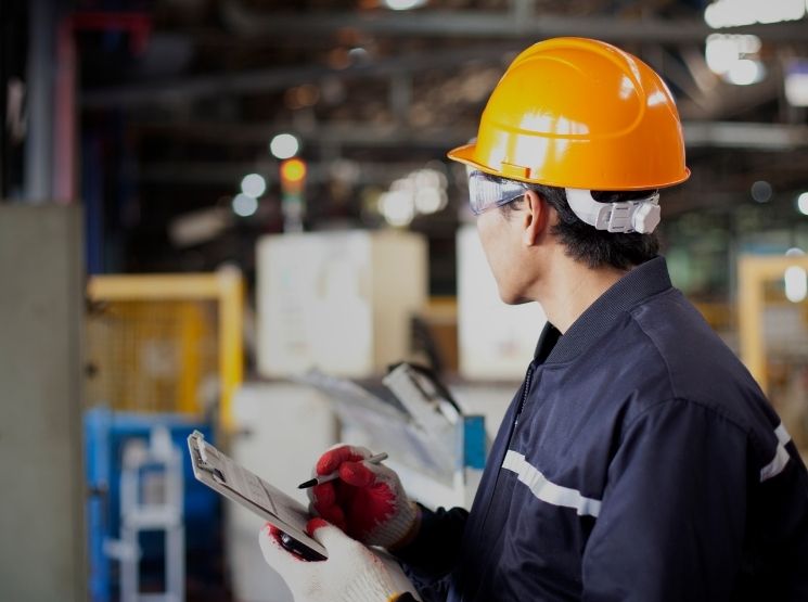 técnico verificando uma prancheta no interior da fábrica
