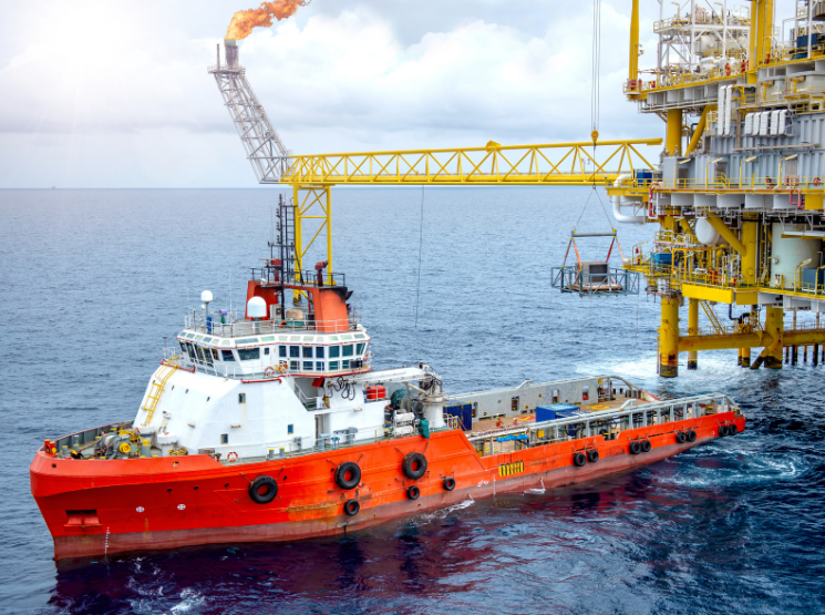 Navio de apoio atracado ao lado de uma plataforma offshore em operação.